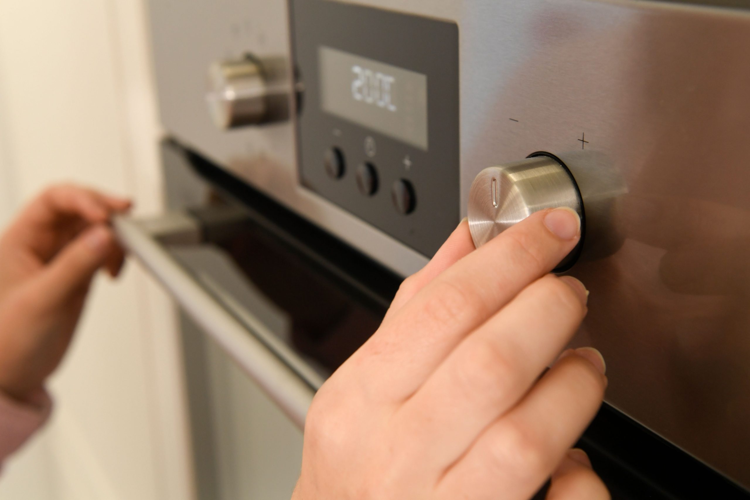 Main réglant le thermostat du four
