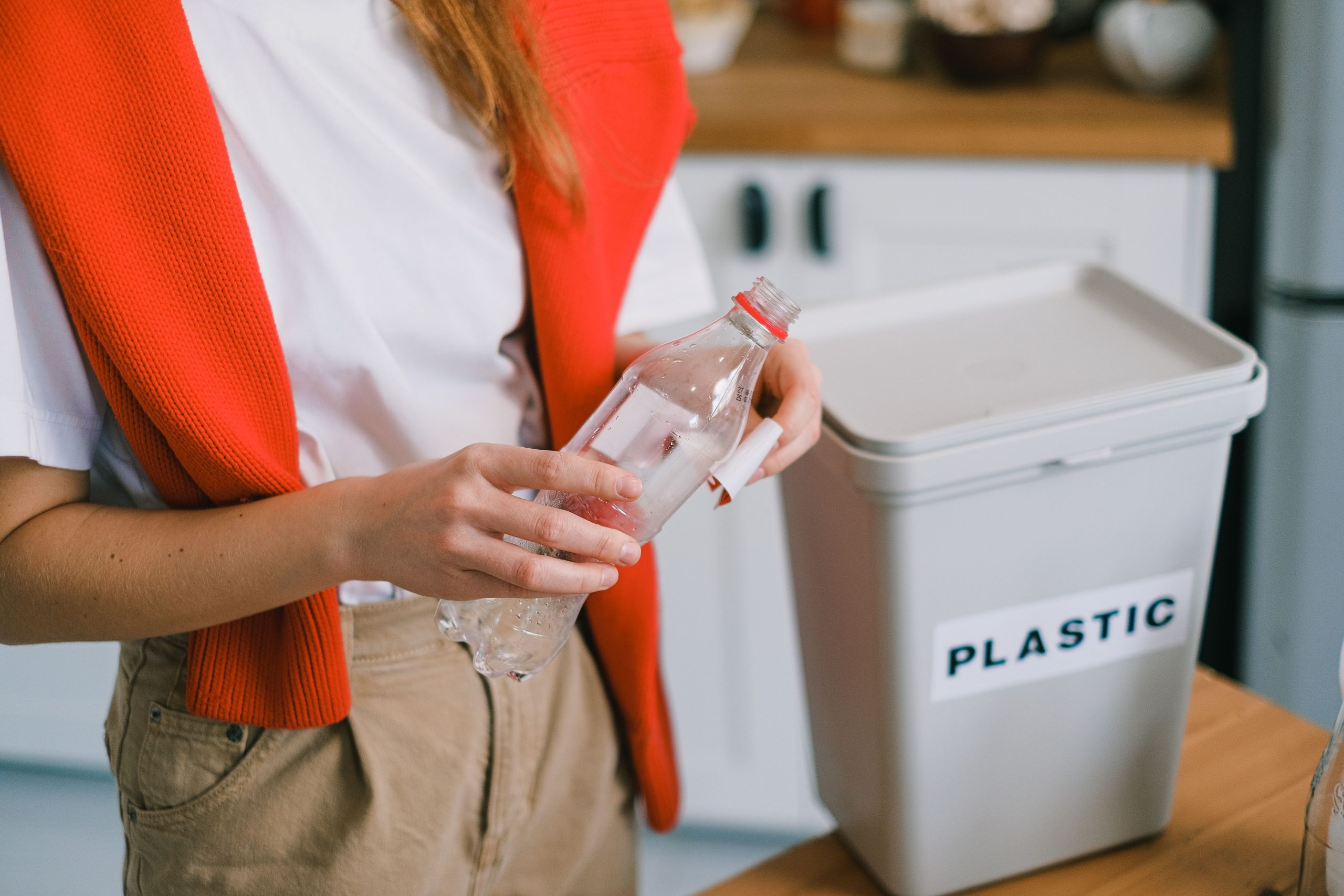 Femme jetant bouteille plastique dans bac recyclage