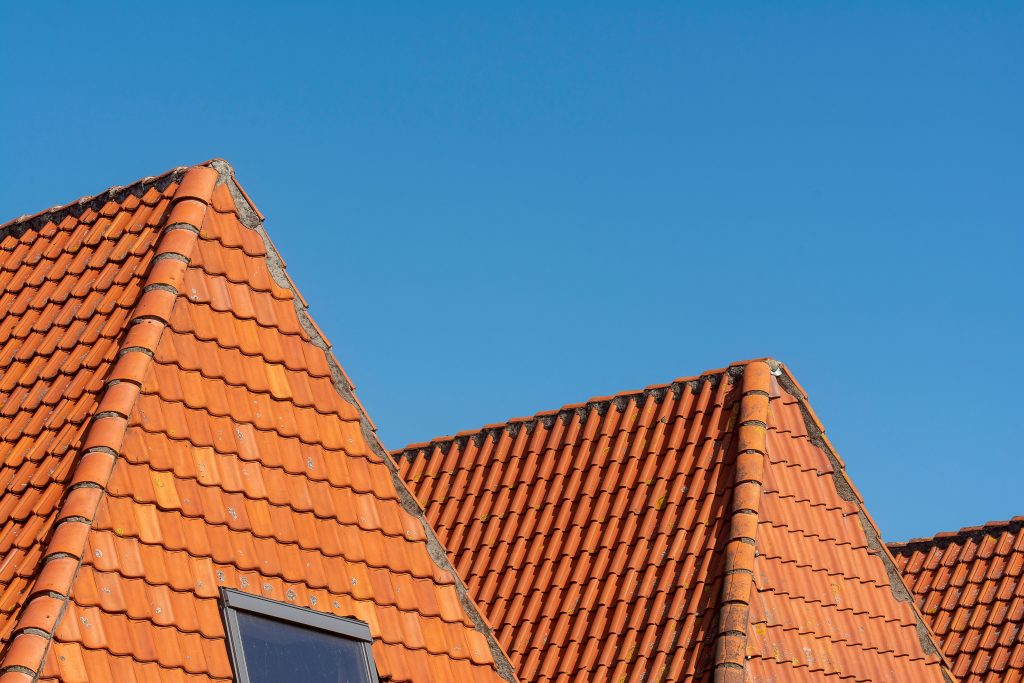 Gros plan de tuiles rouges brillantes sous ciel bleu.