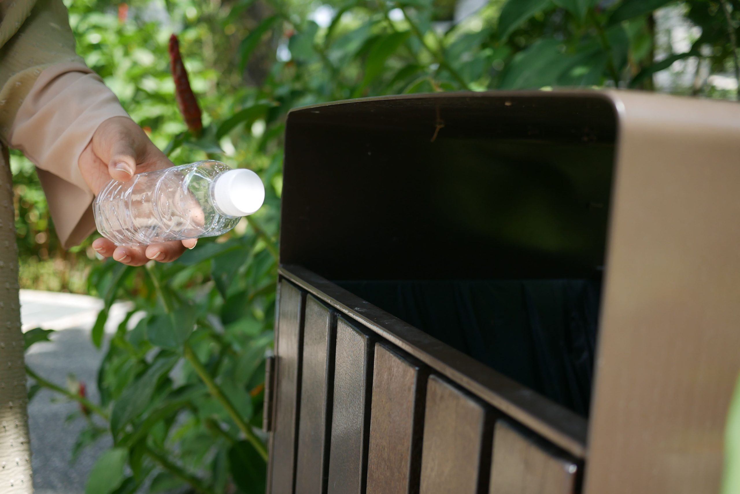 Personne dépose bouteille plastique bac recyclage nature