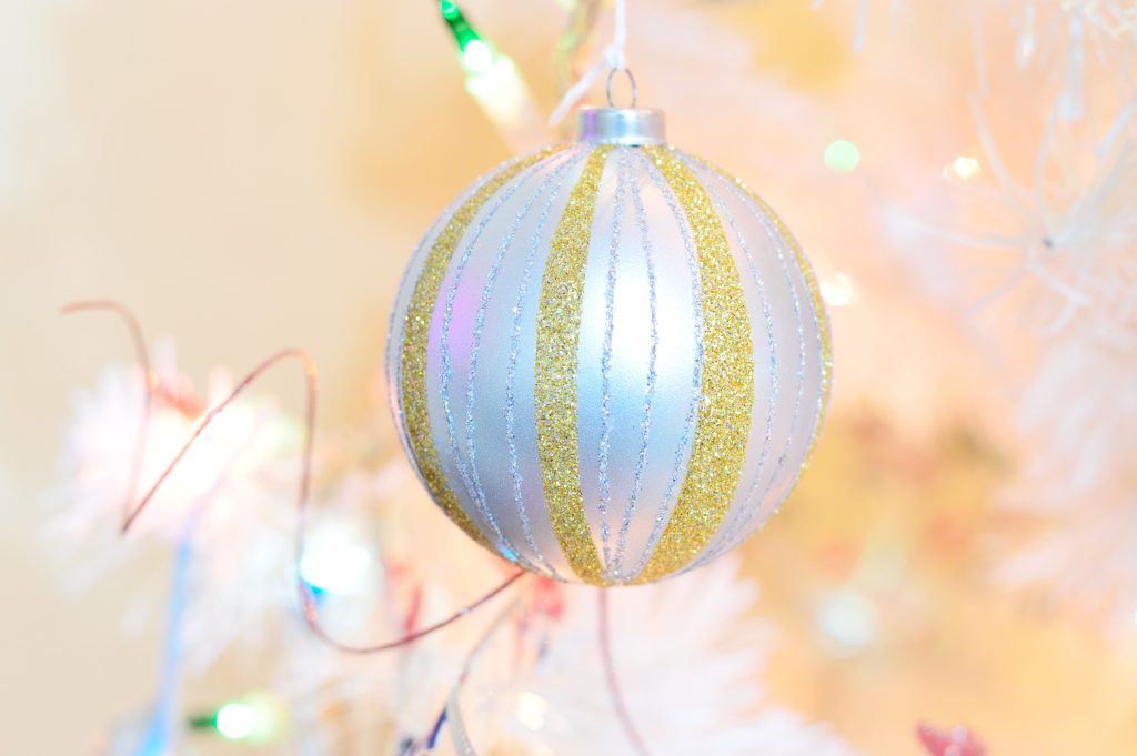 Ornement scintillant or et argent sur sapin blanc