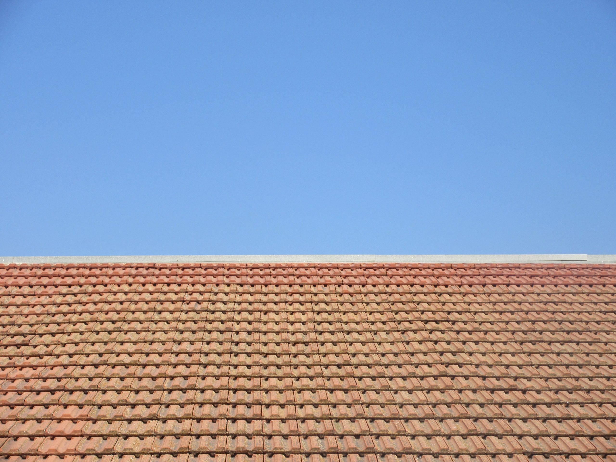 Tuiles terre cuite sous ciel bleu dégagé.