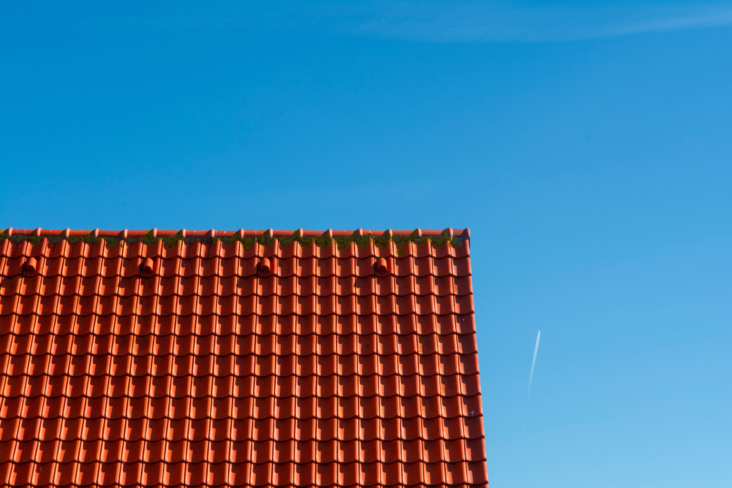 Tuiles rouges de toiture contre ciel bleu clair.