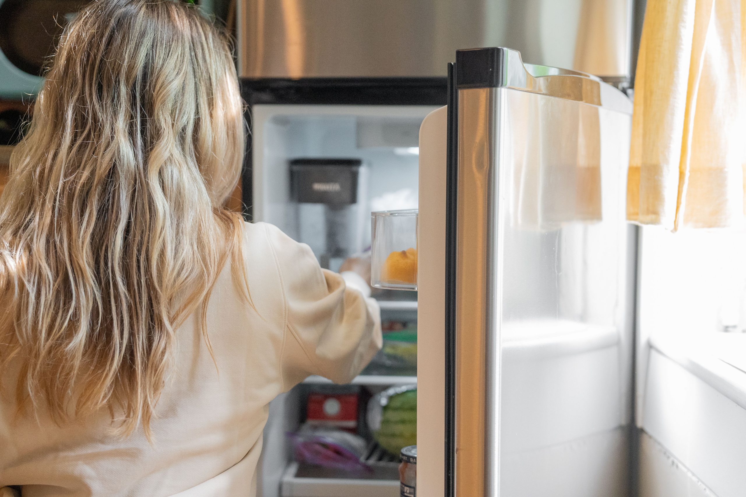 Femme blonde sortant aliments du réfrigérateur cuisine