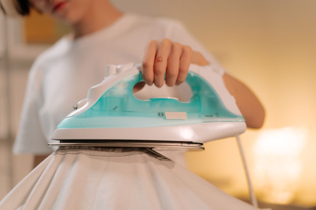 Personne utilisant un fer à vapeur sur un vêtement blanc