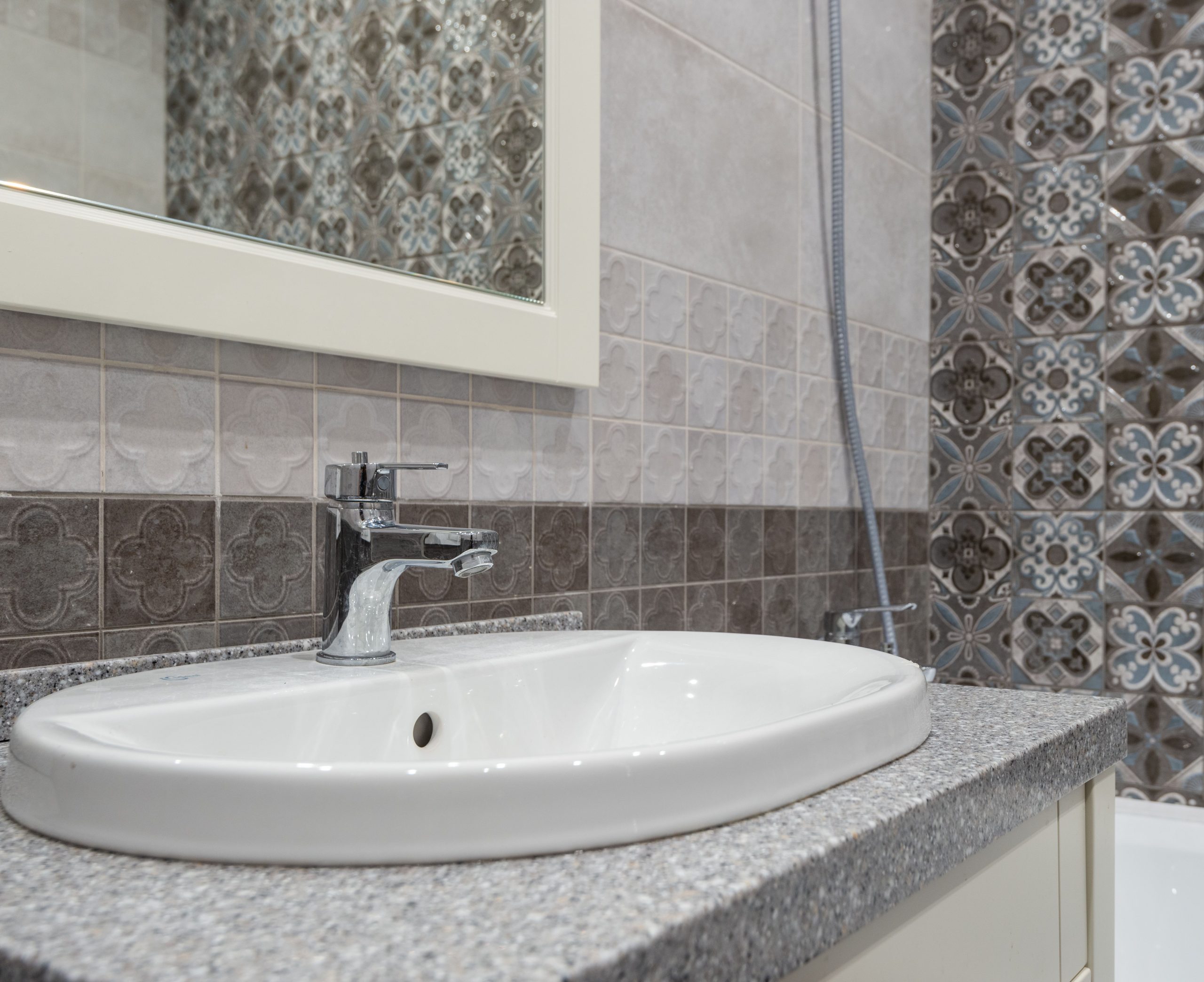 Gros plan lavabo blanc avec carreaux ornementaux salle bain