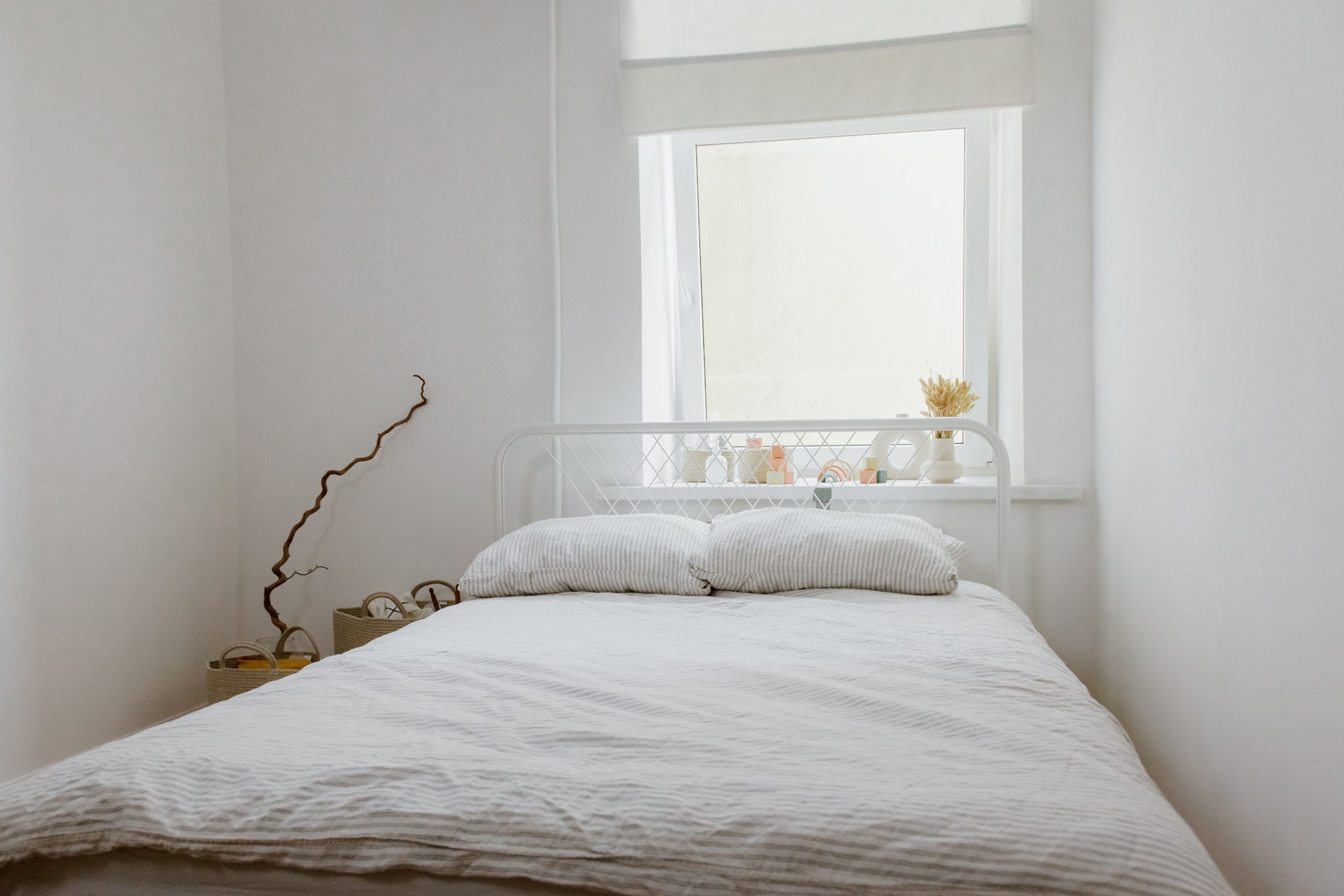 Chambre sereine avec lit blanc et lumière naturelle douce.